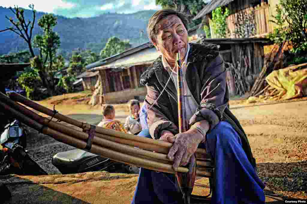 Seorang pria suku asli Thailand bermain alat musik tradisional dari bambu menjelang matahari terbenam di desa Khun Klang, provinsi Chiang Mai, Thailand.