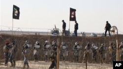 In this file photo provided by the People's Mujahedeen Organization of Iran, Iraqi police stand guard outside the opposition group's camp northeast of Baghdad, Iraq.