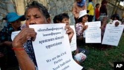 Victims from the civil parties protest for demanding an individual reparation, in front of an entrance of the U.N.-backed war crimes tribunal, as its holding substantial hearing, in Phnom Penh, Cambodia, Friday, Oct. 17, 2014.