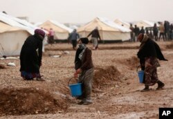 Displaced Iraqis, who fled fighting between Iraqi security forces and Islamic State militants, carry drinking water for their families, in the Hassan Sham camp for displaced people, east of Mosul, Iraq, Dec. 14, 2016.