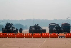 Myanmar's military personnel stand guard at a checkpoint manned with an armored vehicle in a road leading to the parliament building in Naypyitaw, Myanmar.