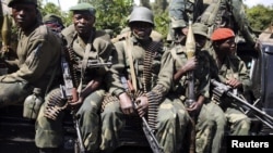 Congolese army (FARDC) soldiers sit in a military truck in Minova, some 45 km (28 miles) west of Goma, November 26, 2012. 