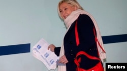 French National Front political party leader and candidate Marine Le Pen collects ballots as she arrives at a polling station during the first round of the regional elections in Henin-Beaumont, France, Dec. 6, 2015. 
