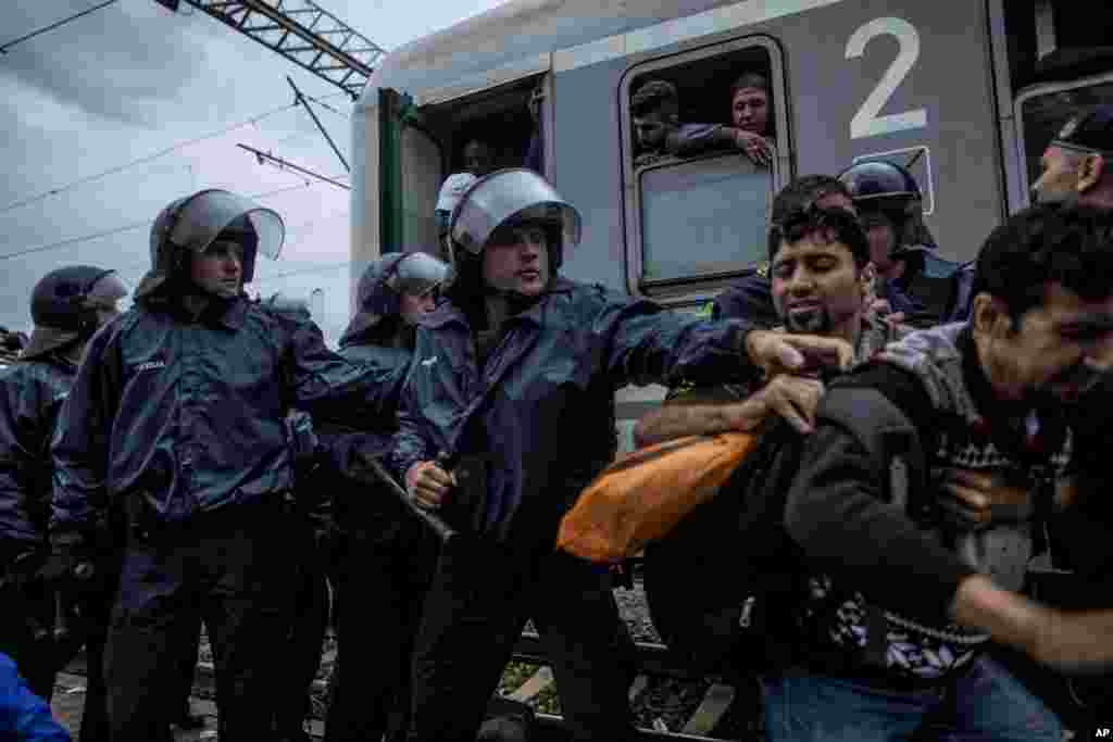 Croatian riot police officers try to clear a railway track after thousands of refugees broke a police line to board a train at the station in Tovarnik.