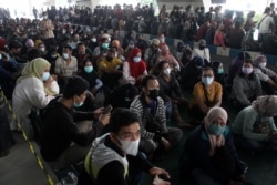 Orang-orang yang memakai masker mengantre untuk mendapatkan vaksin COVID-19 di Bandara Internasional Juanda, saat kasus melonjak di Sidoarjo, Jawa Timur, 22 Juli 2021. (Foto: Antara/Umarul Faruq via REUTERS)