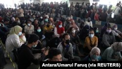 Orang-orang yang memakai masker pelindung mengantri untuk vaksin COVID-19 di Bandara Internasional Juanda, saat kasus melonjak di Sidoarjo, Jawa Timur, 22 Juli 2021. (Foto: Antara/Umarul Faruq via REUTERS)