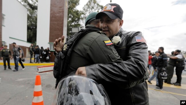 FILE - A man embraces a police officer, outside the General Francisco de Paula Santander Police Academy, a day after a car bomb exploded at the site, in Bogota, Colombia, Jan. 18, 2019.