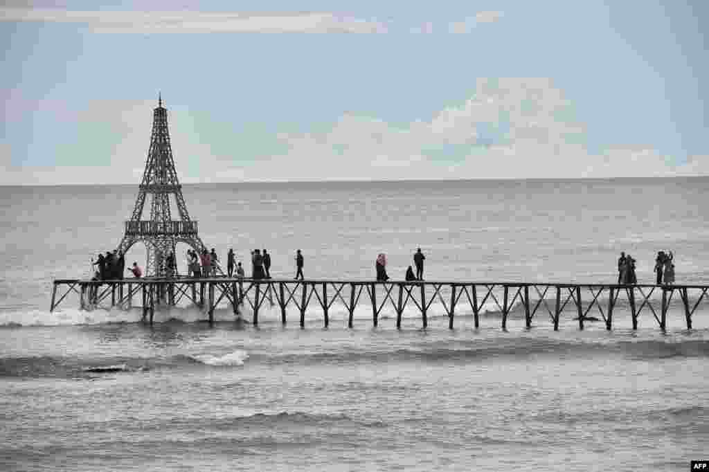 People walk on a pier on Lhokseudu beach, a local tourist attraction in Aceh province, Indonesia.