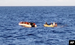 File - An Italian Navy photo taken on Dec. 4, 2014, shows a rescue crew on a dinghy (R) approaching migrants on a boat some 40 miles (65 kilometers) from the Libyan capital, Tripoli.