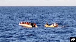 File - An Italian Navy photo taken on Dec. 4, 2014, shows a rescue crew on a dinghy (R) approaching migrants on a boat some 40 miles (65 kilometers) from the Libyan capital, Tripoli.