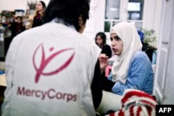 Iman Al Bohtori, right, a Damascus University graduate, talks with a Mercy Corps translator at the 'Melissa' center for migrant women offering various classes and workshops to refugee women in Athens on March 10, 2017.