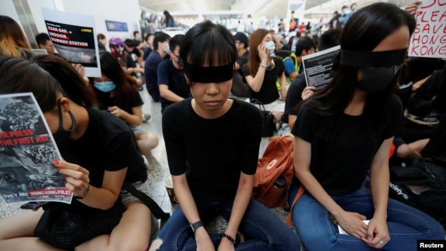 香港反送中示威者在香港國際機場靜坐示威時用黑布蒙眼，抗議警方一天前與示威者的衝突中使一名抗議者眼睛受傷。 (2019年8月12日)