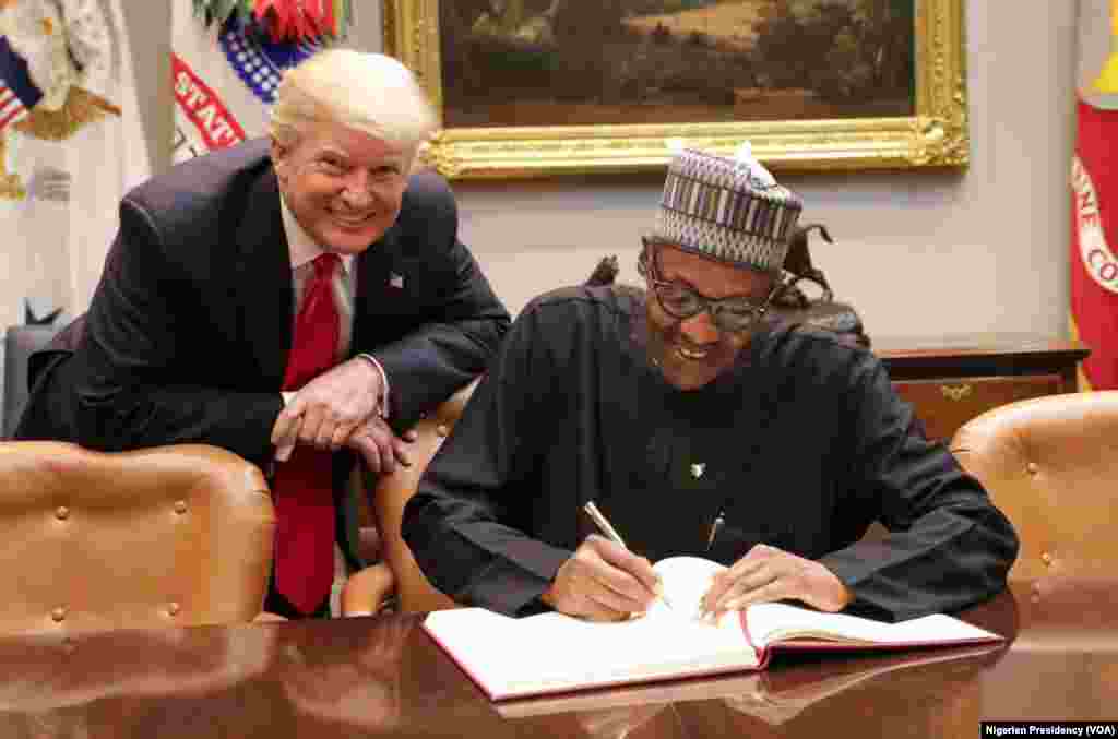 Shugaba Buhari a yayin da yake sa hannun kan wata takarda tare da Shugaba Trump.&nbsp;