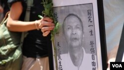 示威人士手持白菊花和李旺陽的遺照以作哀悼