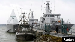 HMS Visby and two minesweepers lie moored at the jetty at Berga marine base outside Stockholm Oct. 22, 2014.