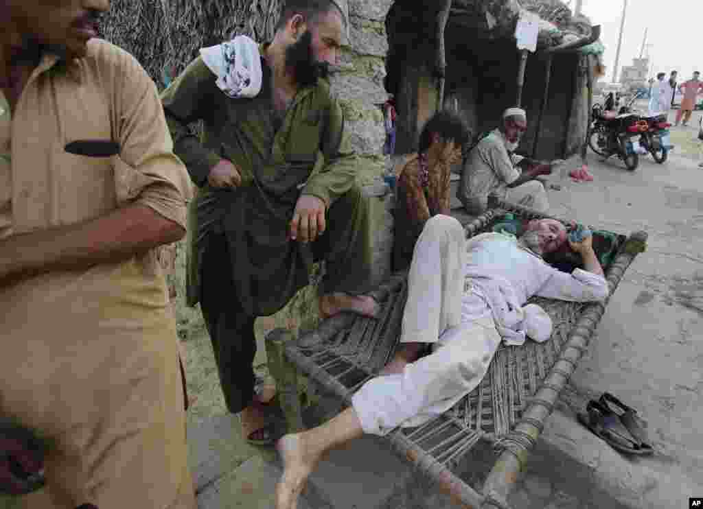 Para pengungsi Afghanistan menunggu kendaraan untuk membawa seorang pria yang sakit ke rumah sakit, di kamp pengungsi di daerah kumuh Islamabad, Pakistan (19/6).&nbsp;(AP/B.K. Bangash)