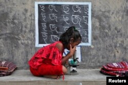 Seorang gadis, yang tidak memiliki akses ke fasilitas internet dan gadget, menggunakan mikroskop saat menghadiri kelas terbuka di luar rumah dengan dindingnya diubah menjadi papan tulis, pasca penutupan sekolah akibat pembatasan terkait COVID-19 di desa Joba Attpara, distrik Paschim Bardhaman, Bengala Barat, India (foto: Reuters).