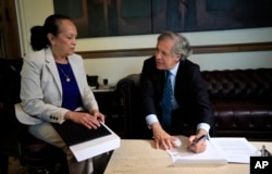 OAS Venezuelan Ambassador Carmen Velasquez, left, watches OAS Secretary General Luis Almagro make notes on the documents she submitted notifying her country's intention to withdraw from the OAS, April 28, 2017.