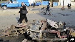 A woman walks past the site of a bomb attack in Baghdad's Shaab District, northern Baghdad, December 22, 2011.