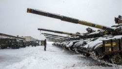 A Ukrainian serviceman stands in front of tanks of the 92nd separate mechanized brigade of Ukrainian Armed Forces, parked in their base near Klugino-Bashkirivka village, in Ukraine's Kharkiv region, Jan. 31, 2022.