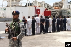 FILE - Navy personnel stand guard as the crew of Silver Sea 2, a Thai-owned cargo ship which was seized by Indonesian authorities last August, are lined up during a media conference at the port of Sabang, Aceh province, Indonesia, Sept. 25, 2015.