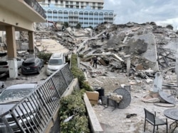 Para petugas penyelamat terus bekerja di reruntuhan gedung apartemen di Miami Beach, Florida, Kamis (24/6).