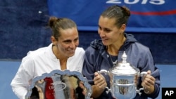 Childhood friends Flavia Pennetta, right, and Roberta Vinci pose with their awards after Pennetta won their women's championship match of the U.S. Open tennis tournament in New York, Sept. 12, 2015.