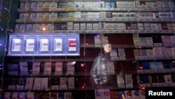 Woman is reflected in a window displaying packs of cigarettes on a street in Russia's Siberian city of Krasnoyarsk, Jan. 24, 2013.