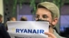 Uma mulher com um cartaz que diz "Onde está Roman (Protasevich)?!" à chegada de avião da Ryanair 