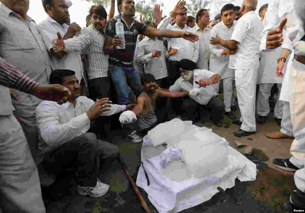 The father (bottom C) of two children, who were burned alive, with his hands bandaged, wails next to the bodies of his children wrapped in white shrouds, as he along with other villagers block a national highway during a protest against the crime at Ballabh in the northern state of Haryana, India, Oct. 21, 2015. Police have arrested four men over allegations that they bured the two low-caste children alive, an official said, a case that triggered a street protest and drew condemnation from an opposition leader.