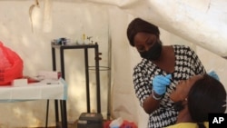 FILE - A woman is tested for COVID-19 in Abuja, Nigeria, Monday Nov. 29, 2021.