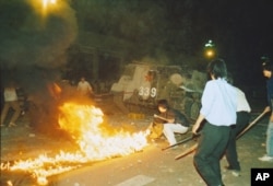 Student protesters put a barricade in front of a burning armored personnel carrier that rammed through student lines, June 4, 1989.