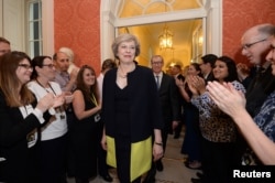 FILE - Staff members applaud as Britain's new Prime Minister Theresa May walks into 10 Downing Street after May met Queen Elizabeth in Buckingham Palace, in central London, Britain, July 13, 2016.