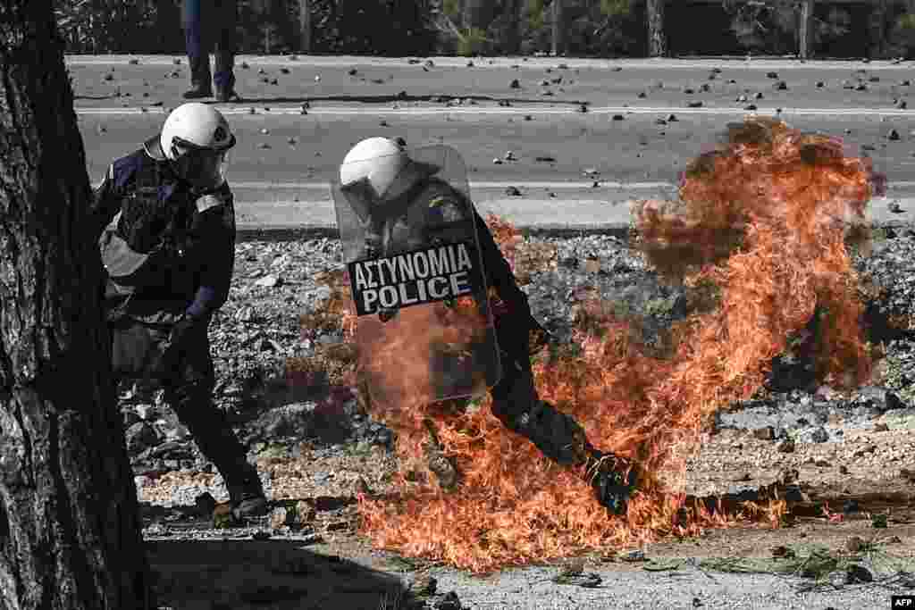 A Greek anti-riot police moves away from flames during clashes with demonstrators protesting against the construction of a new controversial migrant camp near the town of Mantamados on the northeastern Aegean island of Lesbos.