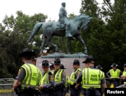 Virginia state troopers stand under a statue of Robert E. Lee before a white supremacists rally in Charlottesville, Va., Aug. 12, 2017.