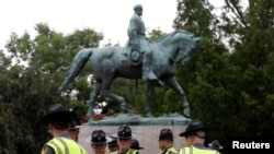 FILE - Virginia state troopers stand under a statue of Robert E. Lee before a white supremacists rally in Charlottesville, Va., Aug. 12, 2017. 