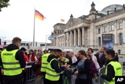 FILE - Visitors to the inaugural mass on the lawn near the Reichstag being checked by security forces before their entry to the grounds in Berlin, Germany, May 24, 2017.
