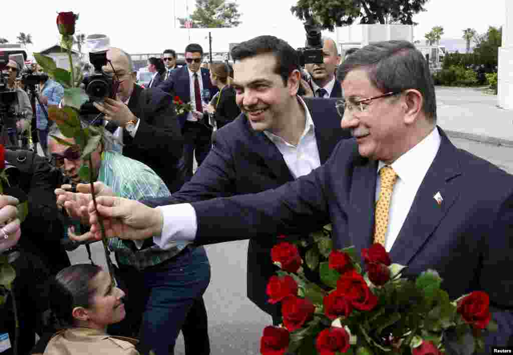 Turkish Prime Minister Ahmet Davutoglu, right, and his Greek counterpart, Alexis Tsipras, present roses to women journalists because of the International Women's Day as they meet in the Aegean port city of Izmir, western Turkey, March 8, 2016. 