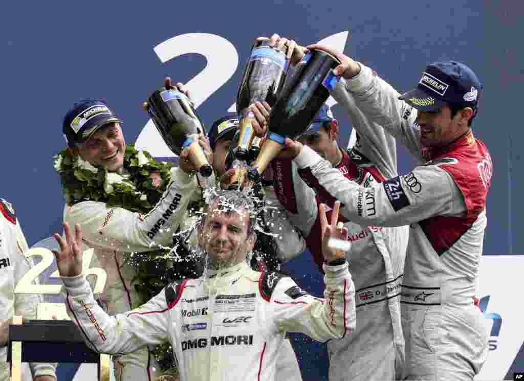 The Porsche 919 Hybrid No2 of the Porsche Team driven by Neel Jani of Switzerland, Romain Dumas of France, Marc Lieb of Germany and Coach driver Jeromy Moore celebrate with champagne, after winning the 84th 24-hour Le Mans endurance race, in Le Mans, western France.