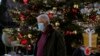 A man wearing a face mask to protect against coronavirus, walks in front of the Christmas tree at Syntagma square in Athens, Greece, Dec. 1, 2021.