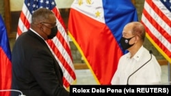 Menteri Pertahanan Amerika Serikat Lloyd Austin (kiri) dan Menteri Pertahanan Filipina Delfin Lorenzana (kanan) berjabat tangan setelah pertemuan bilateral di kamp militer Camp Aguinaldo di Quezon City, Metro Manila, Filipina, 30 Juli 2021. (Foto: Rolex D