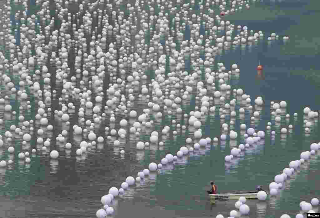 A worker takes a break while arranging &quot;wishing spheres&quot; along Marina Bay in Singapore. People penned their wishes for the New Year onto the spheres before placing them into the river. 