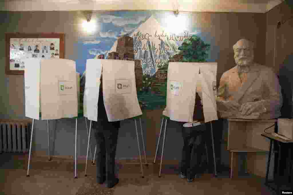 People fill out ballot papers before voting in the presidential election in the village of Alvani, Georgia, Oct. 27, 2013.