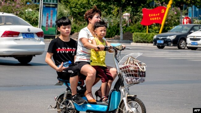 中国某城市的大街上一妇女带着两个孩子