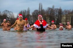 Anggota klub perenang es Berliner Seehunde (Berlin Seals) berendam di Danau Orankesee selama acara renang Natal tradisional mereka di Berlin. (Foto: Reuters)