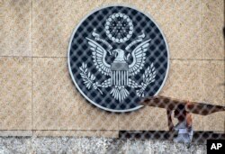 A worker carries cardboard inside the compound of the United States embassy in Havana, Cuba, Sept. 29, 2017.