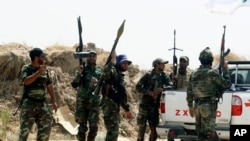 Iraqi security forces and Shiite militiamen stand guard after breaking a siege by the Islamic State extremist group on Amirli, north of Baghdad, Iraq, Aug. 31, 2014.