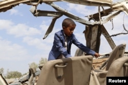 FILE - Hafidh Abdullah al-Khawlani, who survived a Saudi-led air strike stands on the wreckage of a bus destroyed by the strike in Saada, Yemen Sept. 4, 2018.
