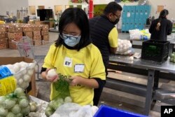 Para sukarelawan mengemas bawang di gudang Bank Makanan Komunitas Alameda County di Oakland, California, 5 November 2021.