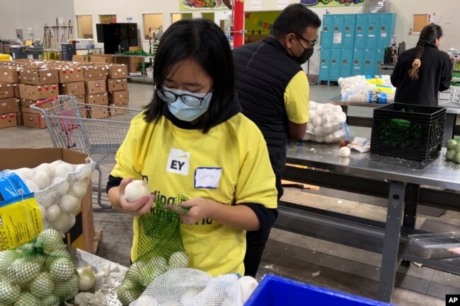 Para sukarelawan mengemas bawang di gudang Bank Makanan Komunitas Alameda County di Oakland, California, 5 November 2021.